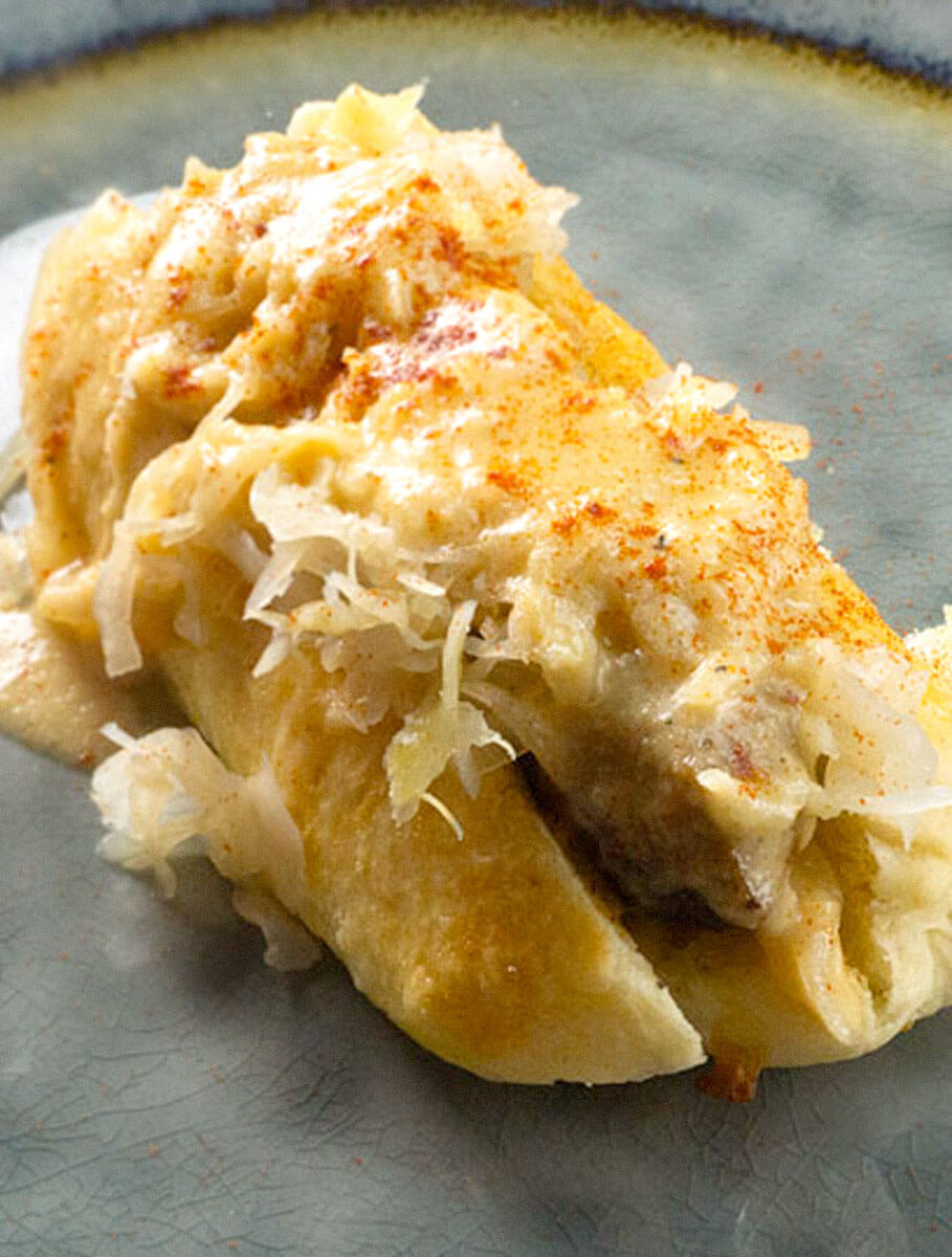 WisconsinBeerBrat2-2 Beer Brat, with onions on a bun on blue and yellow plate on a wooden cutting board