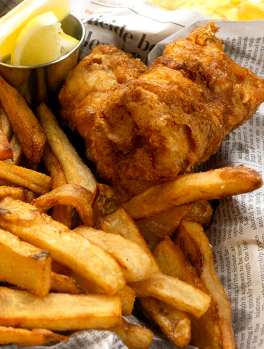 BeerBatterFishandChips2-2 Beer Battered Fish and Chips on a newspaper with cut up lemon in a metal sauce up