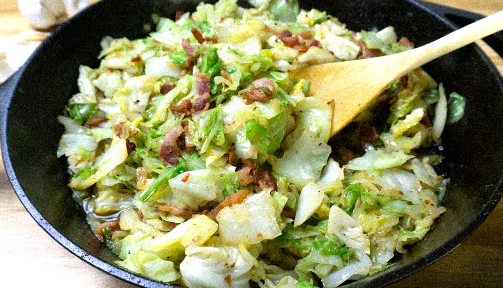 fried cabbage and bacon in a cast iron pan.