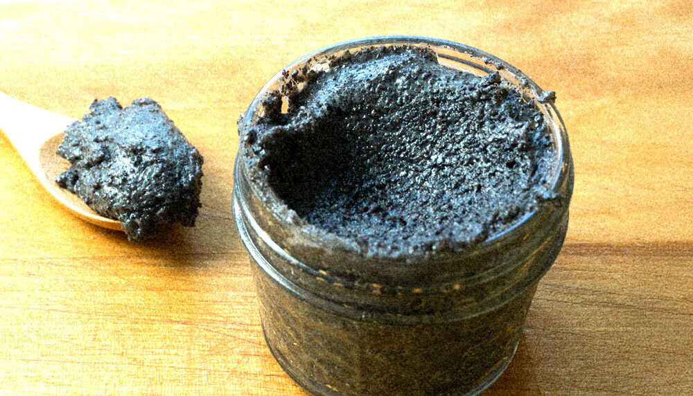 poppy seed filling in a glass jar with a wooden spoon on the side.