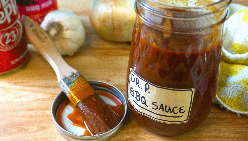 Glass mason jar with sauce on wooden cutting board with brush
