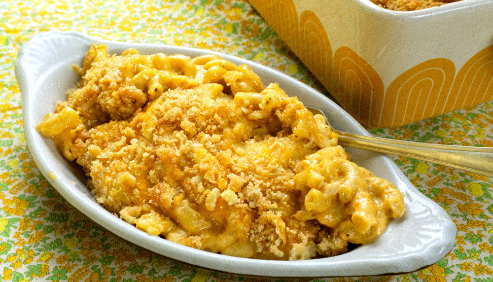 macaroni and cheese in a oval dish with a baking dish in the background.